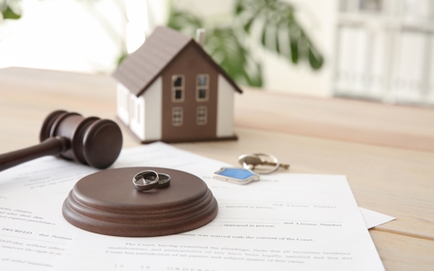 house, keys, gavel and rings sitting on a desk
