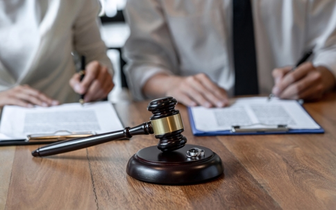 gavel on a table in front of two people signing paperwork